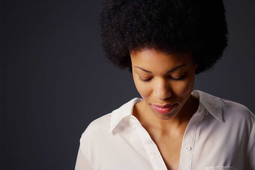 African-American woman gazing down in front of a black background
