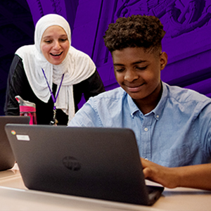 A student works on a laptop as an NYU Teacher Resident supports their learning.