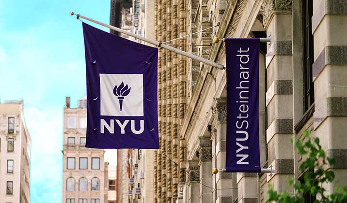 An NYU banner and flag hangs on a campus building.
