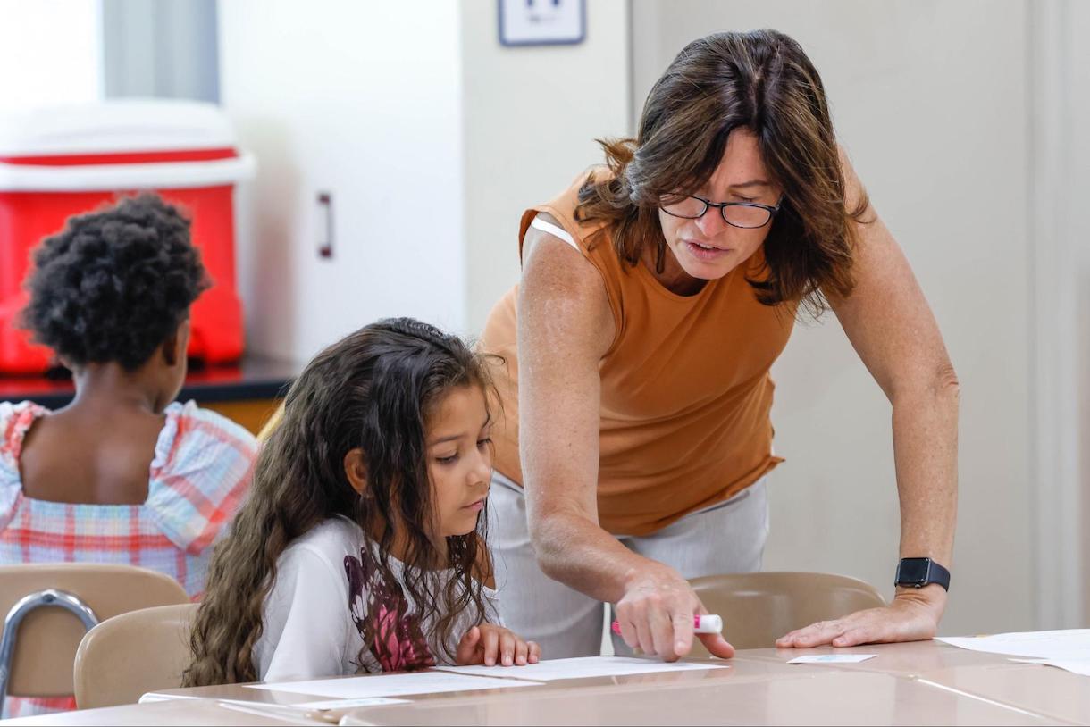 A Rochester City School District teacher works with a student at a desk