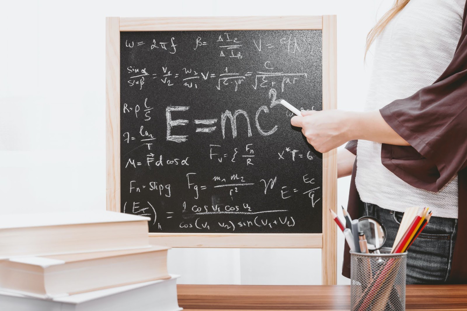 A teacher writes a math equation on a small chalkboard.