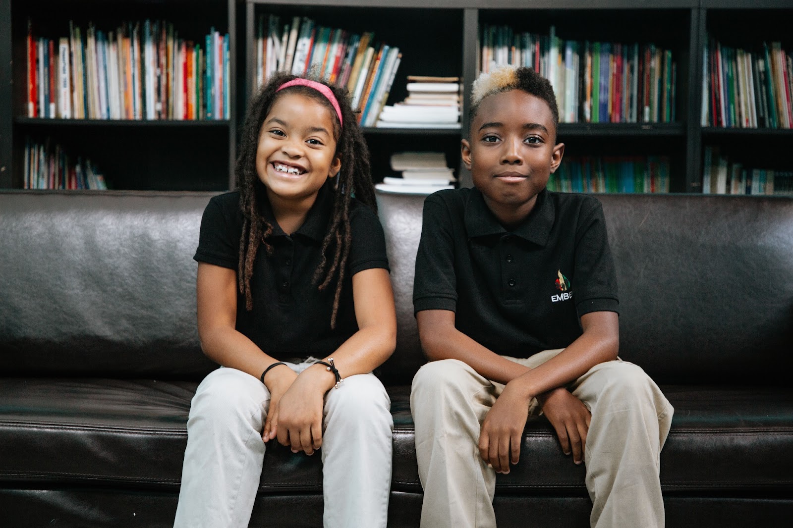 Two Ember Charter Schools students sit on a bench in the school library.
