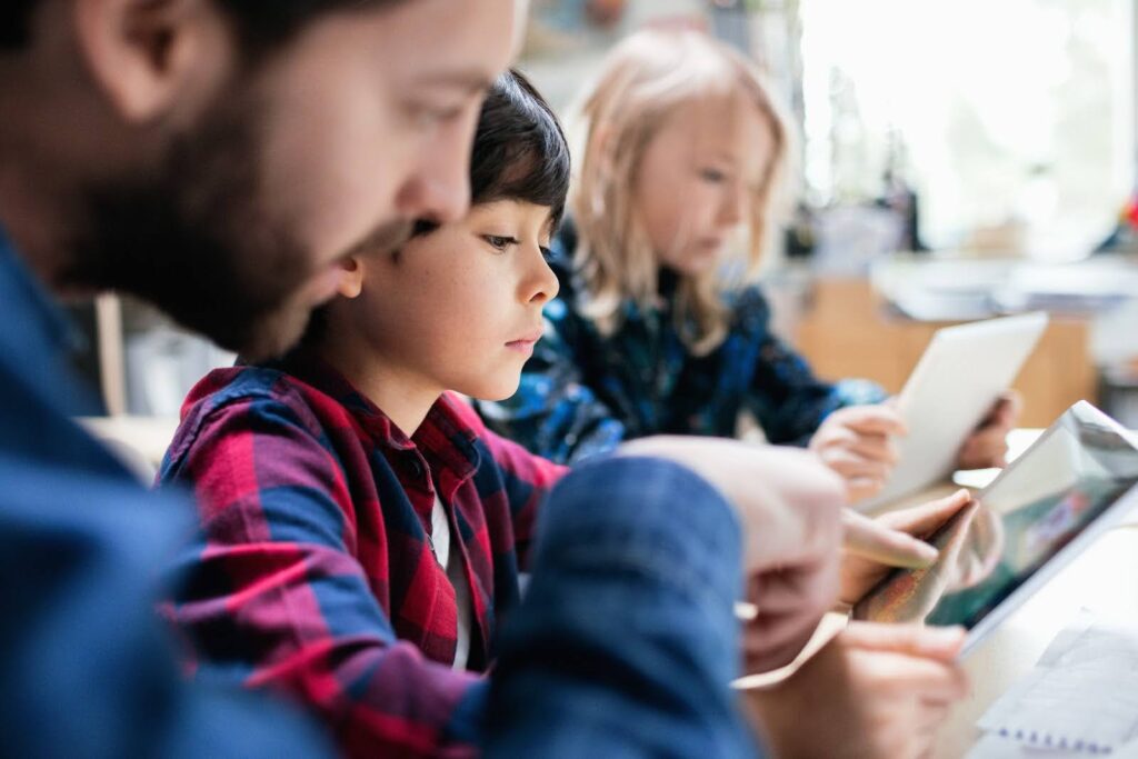 Close-up of a teacher explaining to students how to use a digital tablet.